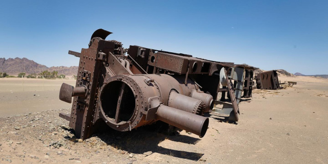 A rusting train lays on its side in the desert