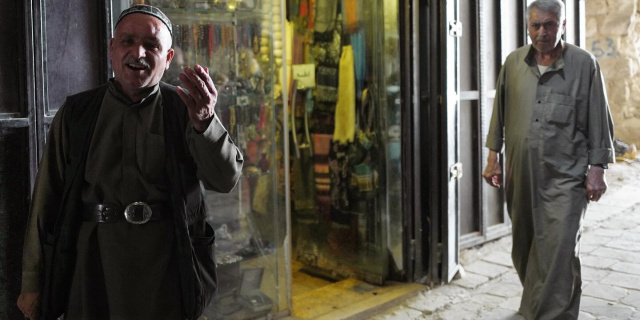 Two men stand outside a shop in the famed souks of Aleppo, Syria